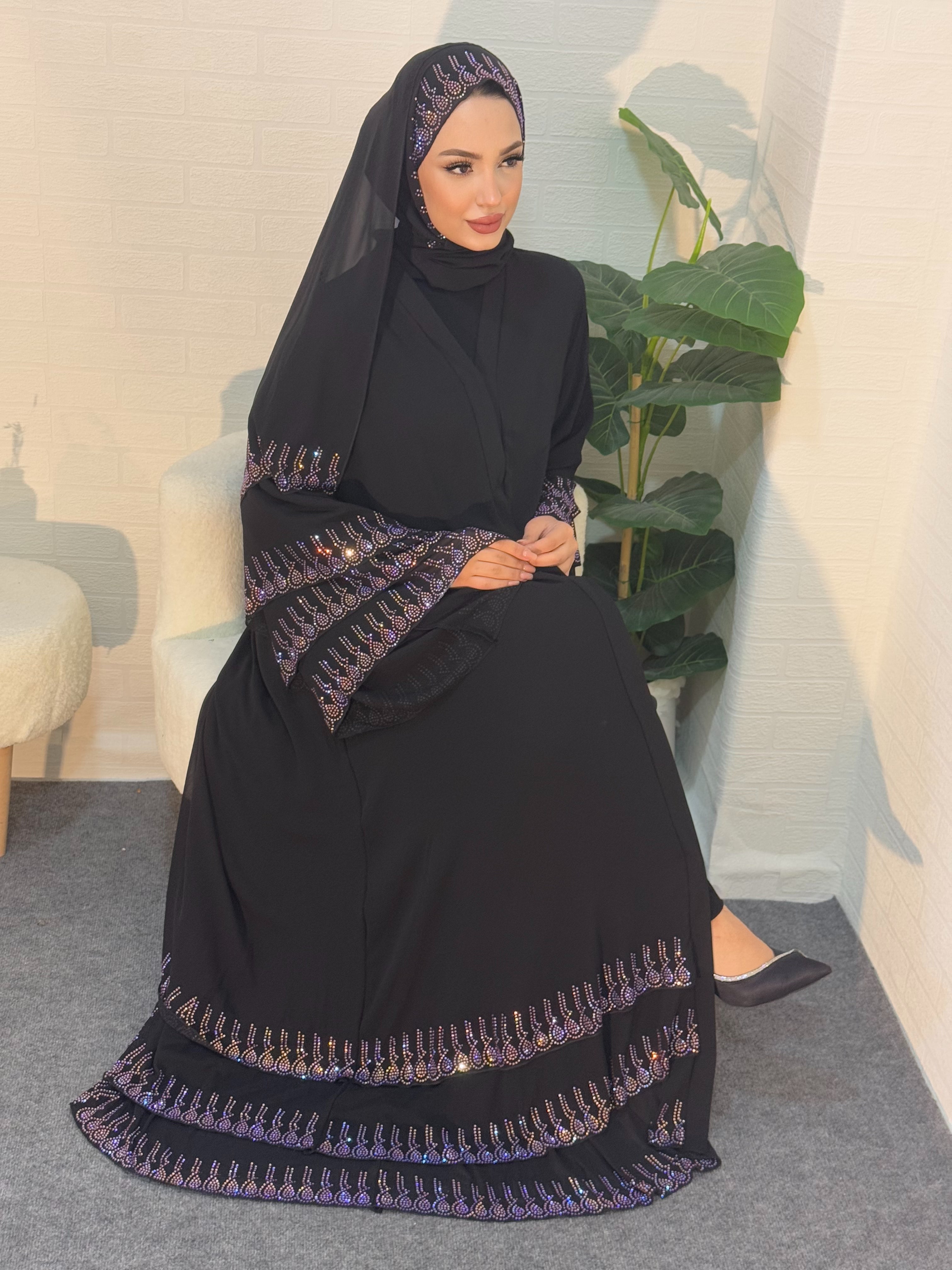 عباية سوداء مع أحجار أرجوانية على أطراف التنورة